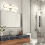 Modern bathroom with a dark marble countertop, wooden vanity, rectangular mirror, potted plant, toilet, glass-enclosed shower, and a sleek, illuminated wall light above the mirror.