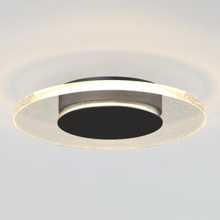 The Artika Essence Disk LED flush mount features a modern circular design with a black center and clear surrounding ring, providing a gentle, subtle ceiling glow.