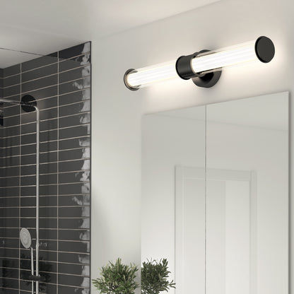 A modern bathroom features the Artika Kendra LED contemporary bathroom vanity light (3 CCT) above a large mirror, gray tiled shower with a handheld showerhead, and green plants on the counter.