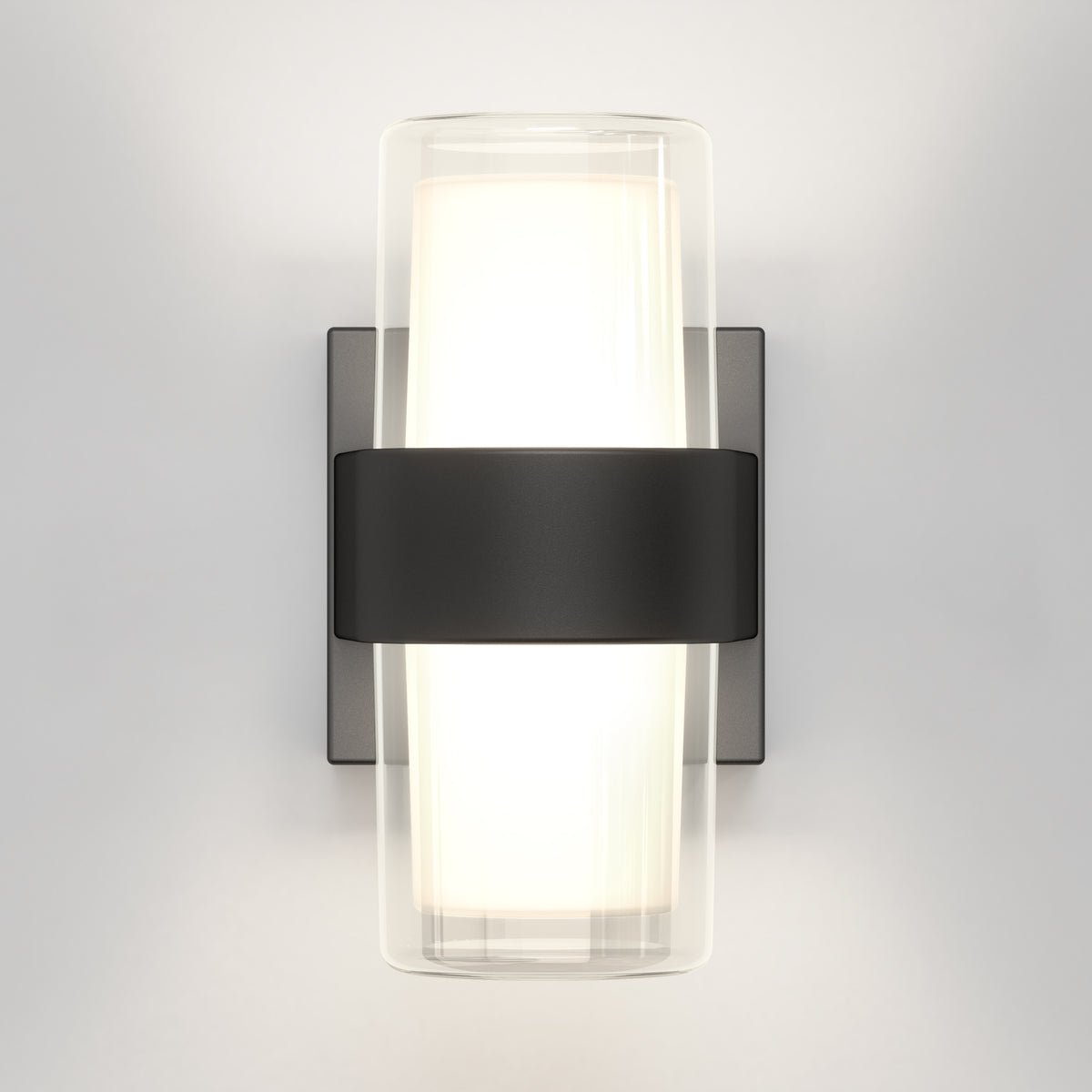 The Artika Colton modern LED indoor-outdoor wall light 5 CCT features a frosted glass cylinder illuminated and held by a wide matte black band, mounted on a rectangular backplate against a light gray wall.