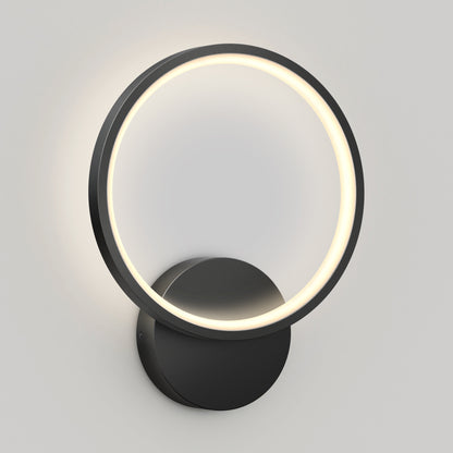 The Artika Solis modern LED indoor-outdoor wall light 5 CCT features a circular LED ring with a black frame on a round base, casting a soft glow against a light gray wall.