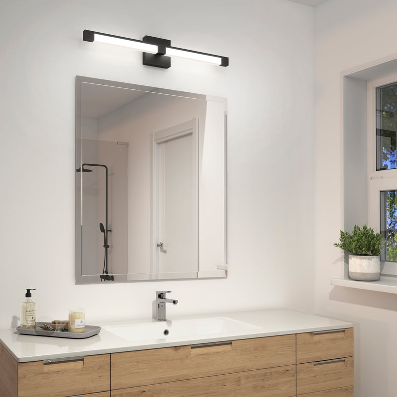 A modern bathroom showcases a large square mirror above a wood vanity with a white countertop, soap dispenser, and tray. Above the mirror is the Artika Tivoli modern LED bathroom vanity light 5 CCT. A window sits to the right.