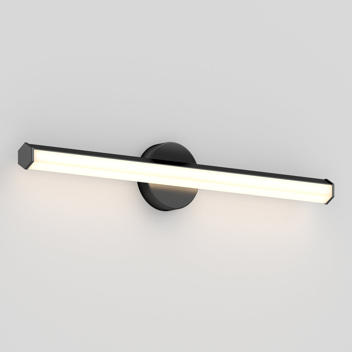 A modern wall-mounted LED light fixture with a black circular base and a long, horizontal, rectangular light bar, emitting a soft white glow against a plain light gray wall.