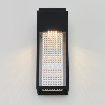 The Meteor LED indoor/outdoor wall light by Artika-CAN-dev features a black rectangular design with a perforated front panel. Mounted on a light gray wall, it casts patterned light through its holes for a striking effect.