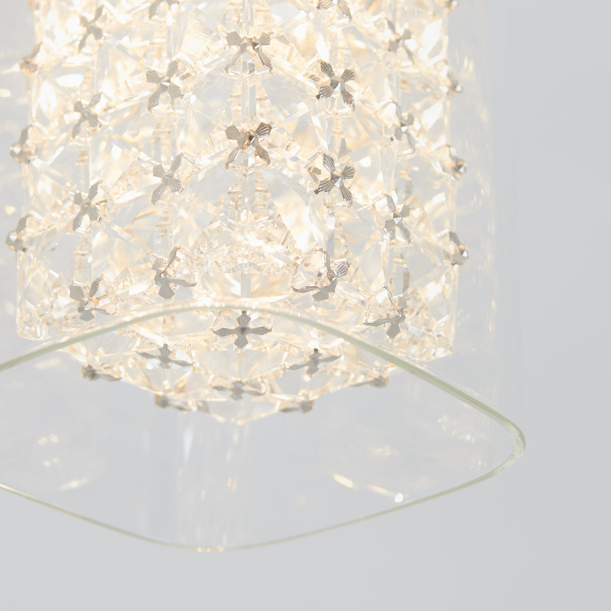 Close-up of Artikas Crystal Cube 1-light LED pendant light featuring a geometric, crystal-like design and soft white glow, partially framed by a clear glass panel against a plain light background.