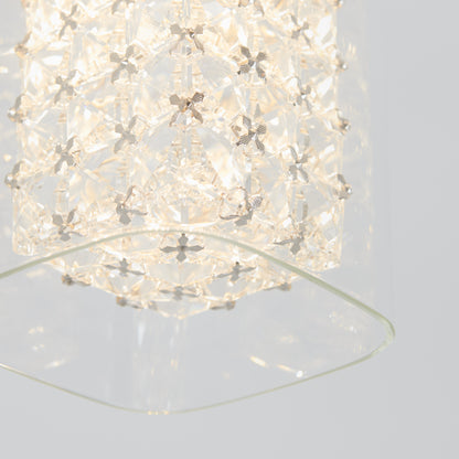 Close-up of Artikas Crystal Cube 1-light LED pendant light featuring a geometric, crystal-like design and soft white glow, partially framed by a clear glass panel against a plain light background.
