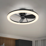 A modern ceiling fan with three black blades is encircled by a glowing LED ring light, mounted on a white ceiling in a contemporary room with minimal decor.