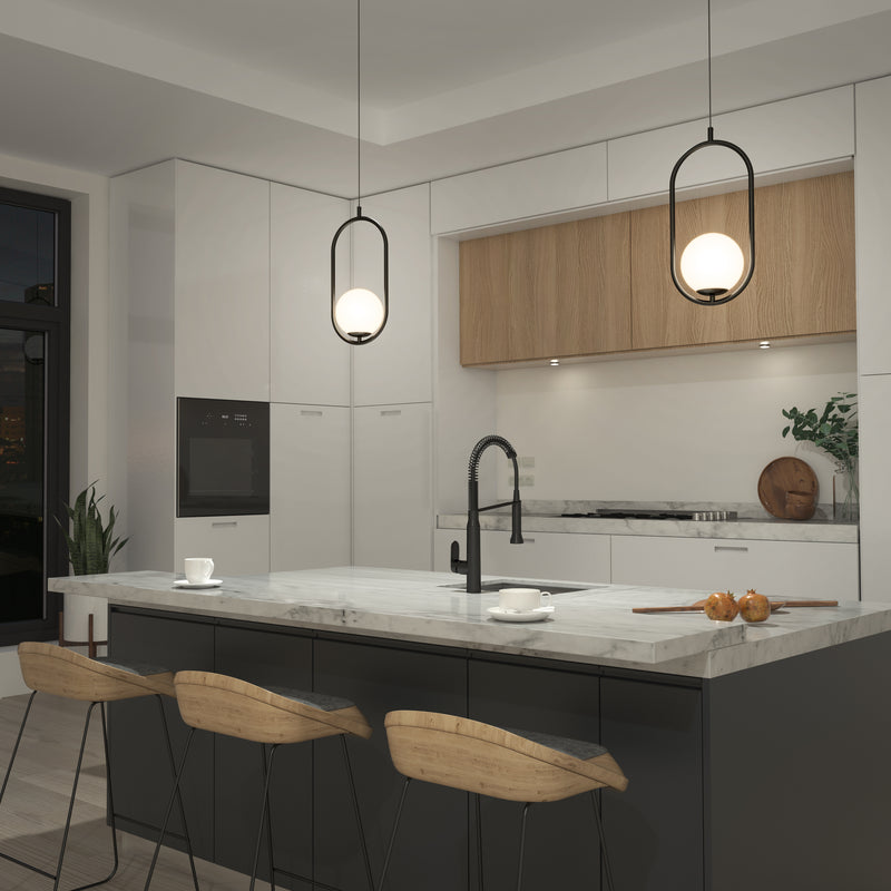 Modern kitchen with a marble island, three wooden bar stools, built-in appliances, and minimalist white and wood cabinetry. Bloom mid-century LED pendant lights by Artika hang above. A few cups and fruit are on the island.
