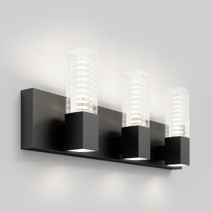 The Artika Hologram LED modern bathroom vanity light features three black rectangular bases with clear glass covers showcasing a geometric layered design, emitting soft white light for a stylish, contemporary look.