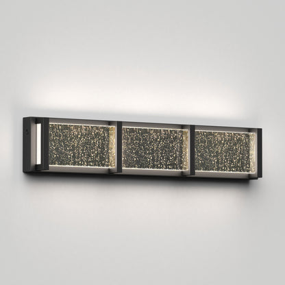 The Artika Subway Essence 3 LED bathroom vanity light features three rectangular, bubble-textured illuminated panels in a sleek dark frame, perfect for mounting on a light gray wall.