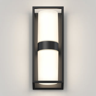 The Artika Sherman modern LED indoor-outdoor wall light 5 CCT features a rectangular black frame and cylindrical frosted glass shade, mounted vertically on a light gray wall for soft, even illumination.
