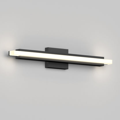 The Artika Ophelia modern LED bathroom vanity light 5 CCT is a sleek, rectangular wall fixture with a black base and an illuminated white panel, casting soft light on a gray wall.