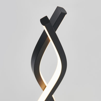 Artikas Wave LED Table Lamp features two modern black curved fixtures that elegantly twist together, emitting a soft glow against a plain gray background.