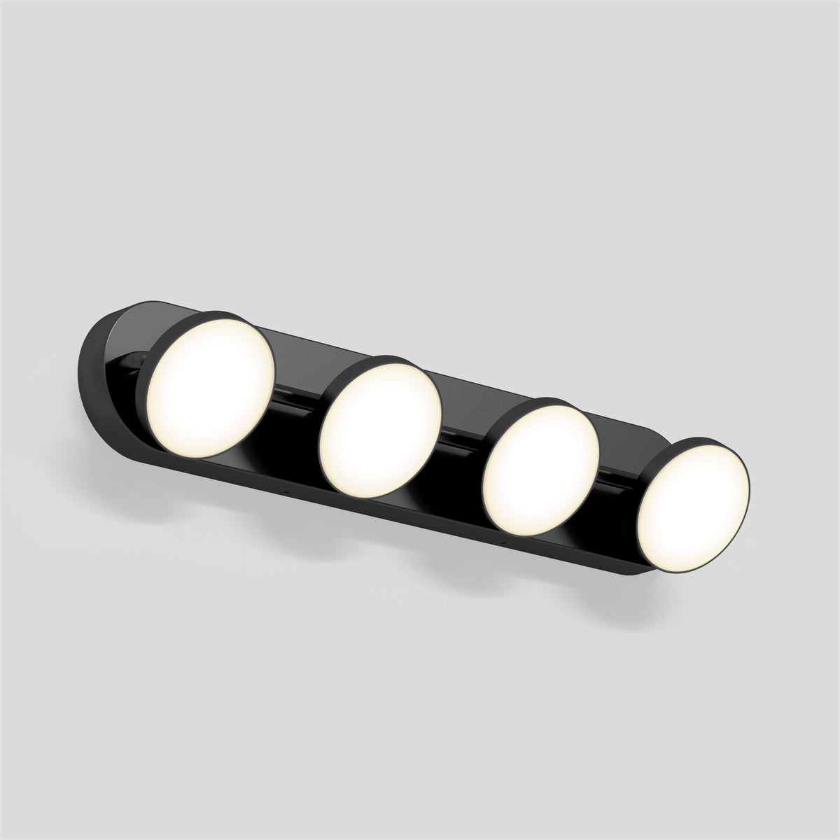 A modern wall-mounted light fixture with four round, evenly spaced LED lights on a sleek black base, set against a plain light gray background.