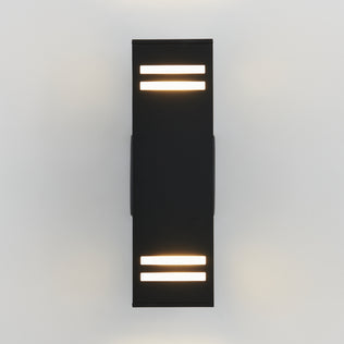 The Artika Strike indoor-outdoor wall light is a modern black sconce with horizontal light strips on the top and bottom, mounted on a white wall and casting soft, warm light both upward and downward.