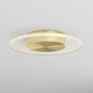 The Artika Essence Disk LED flush mount is a modern ceiling light with a circular gold base and a clear, ring-shaped rim with subtle sparkles, designed for white ceilings.