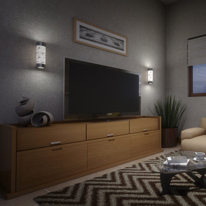 A modern living room features a large TV on a wooden cabinet, abstract decor, patterned rug, coffee table with magazines, potted plant, framed picture, window with blinds, and Artika Bubble Element LED indoor-outdoor lights.
