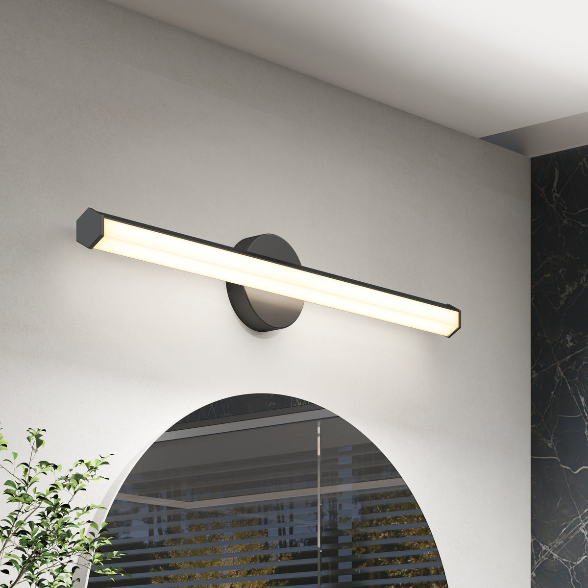 The Artika Ewen modern LED bathroom vanity light 5 CCT shines above a rounded mirror, lighting a white wall with black and green decor.