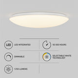 A round, white LED ceiling light is mounted on a gray ceiling. Below it are icons and text indicating features: LED integrated, 50,000 hours lifespan, dimmable, selectable white technology, and 1250 lumens brightness.
