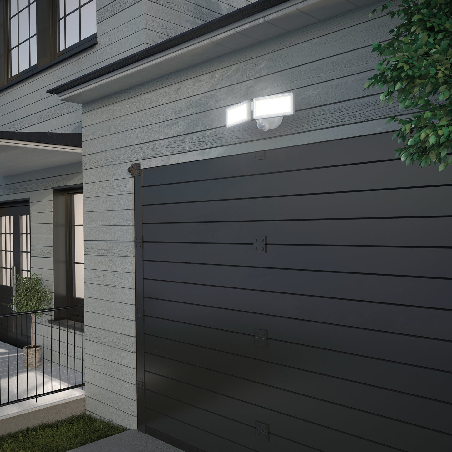 A modern garage with dark horizontal panels is attached to a light gray house. Two Artika Sentinel outdoor Flat Panel Security lights are mounted above the garage door beside a leafy green tree.