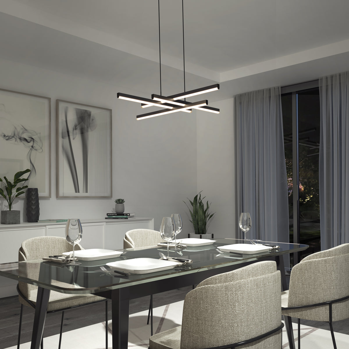Modern dining room with a glass table set for four, beige upholstered chairs, abstract wall art, potted plants, and a contemporary geometric chandelier hanging from the ceiling. Large window with sheer gray curtains.