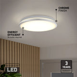 A round ceiling light with a chrome finish and integrated LED, mounted on a white ceiling above a wooden accent wall. Text highlights energy efficiency, no bulbs required, and a 3-year warranty.