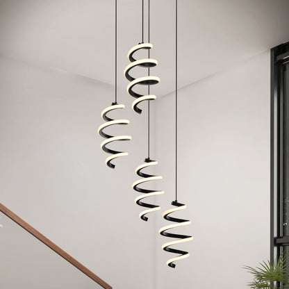 The Artika Chorus 4 Light LED Pendant (5 CCT) hangs from the ceiling in a bright, minimal room with white walls, a staircase railing, and a plant visible in the lower right corner.