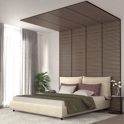 A modern bedroom features a beige upholstered bed with green blanket and mauve pillows. Behind the bed, the Artika-CAN-dev Sonolok 15.5 ft sound-absorbing wall panel kit creates a vertical accent extending onto the ceiling.