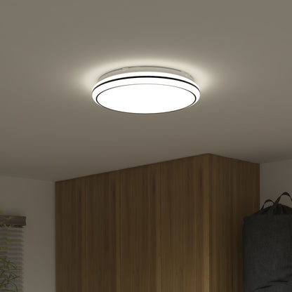 The Artika Emina 13 in. LED flush mount light offers 3 CCT options and emits 800 lumens, casting a soft glow on a white ceiling above a wooden wardrobe in a minimally decorated room.