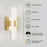 A modern wall sconce with vertical LED tubes and a brushed gold base, next to icons and text highlighting features: LED integrated, dimmable, 50,000 hours, 600 lumens, easy installation, and selectable white technology.