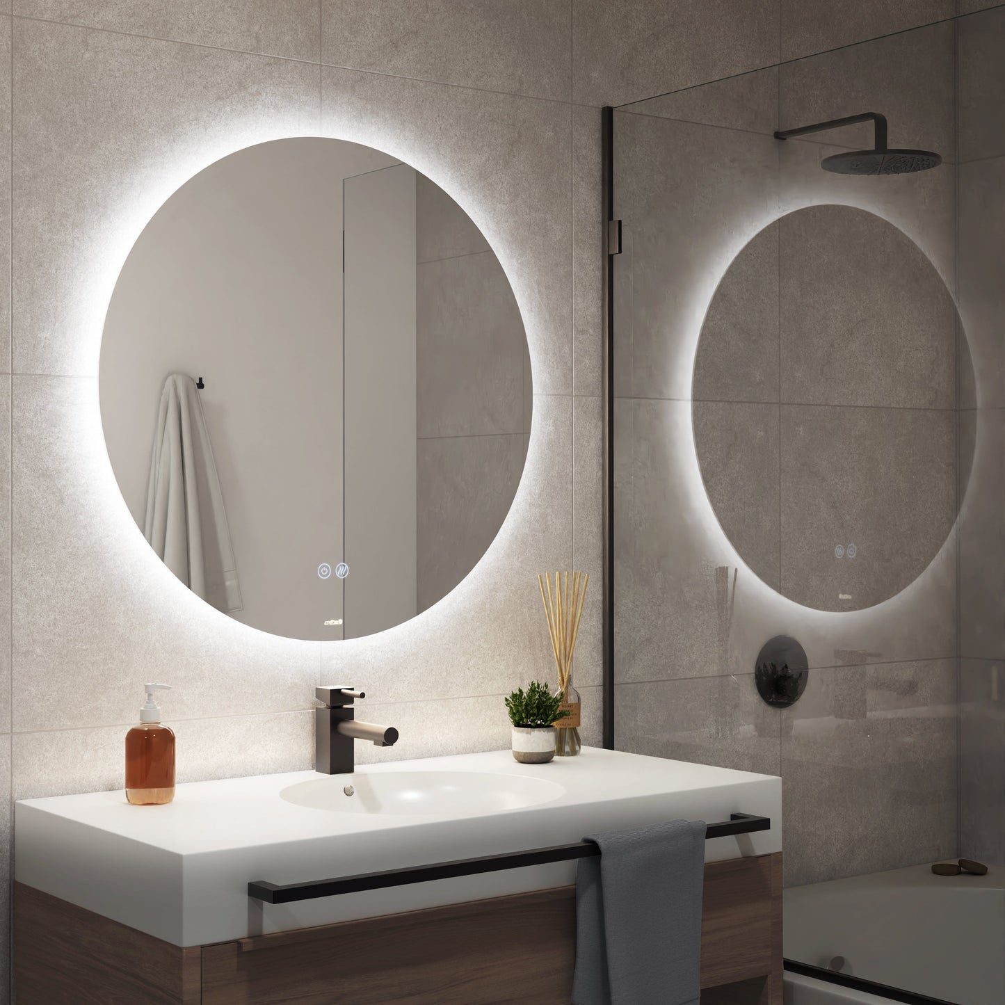 A modern bathroom features the Artika-CAN-dev Raya 24 in. LED mirror (3 CCT, defogger) above a white sink with a black faucet, counter towel, soap dispenser, plant, reed diffuser; wall towel and shower also visible.