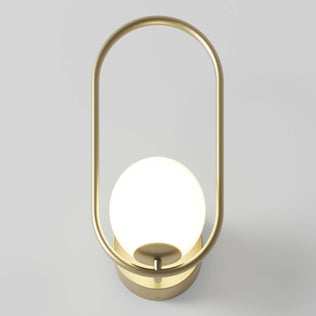 The Artika Bloom LED Sconce 3 CCT features a modern gold metal oval frame with a round, glowing white bulb at its center, shown mounted on a light-colored wall.
