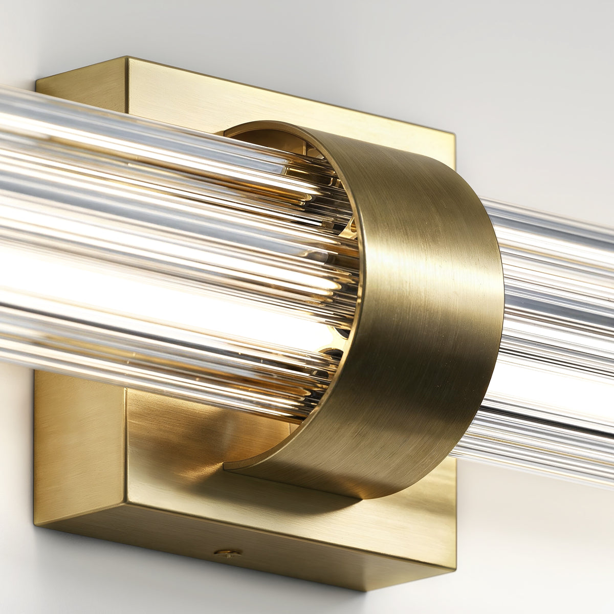 Close-up of Artika Dorado 27 in. 1-Light LED Wall Vanity, 5CCT, dimmable brass sconce with clear glass rods and square backplate.