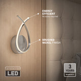 Modern wall sconce with a brushed nickel finish and integrated LED light is mounted on a wooden wall next to a tufted upholstered headboard. Text highlights energy efficiency and a 3-year warranty.