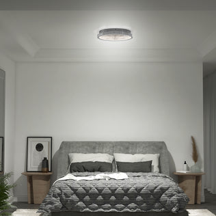 A modern bedroom with a gray upholstered bed, checkered bedding, side tables, and the Artika Glitter LED flush mount ceiling light.