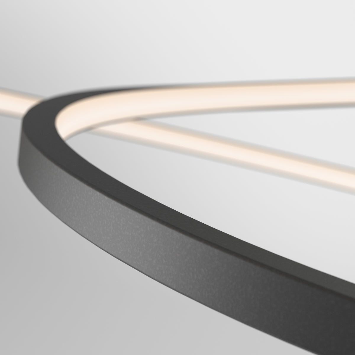 Close-up of a modern, curved light fixture with a black frame and a soft white glow, set against a minimal, light gray background.