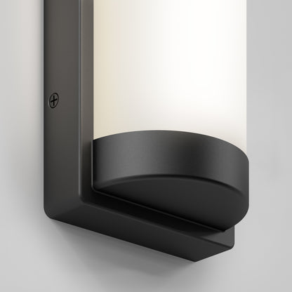 A close-up of the Artika Fogo modern LED indoor-outdoor wall light 5 CCT, featuring a matte black rectangular base and cylindrical frosted white diffuser, mounted on a light-colored wall.