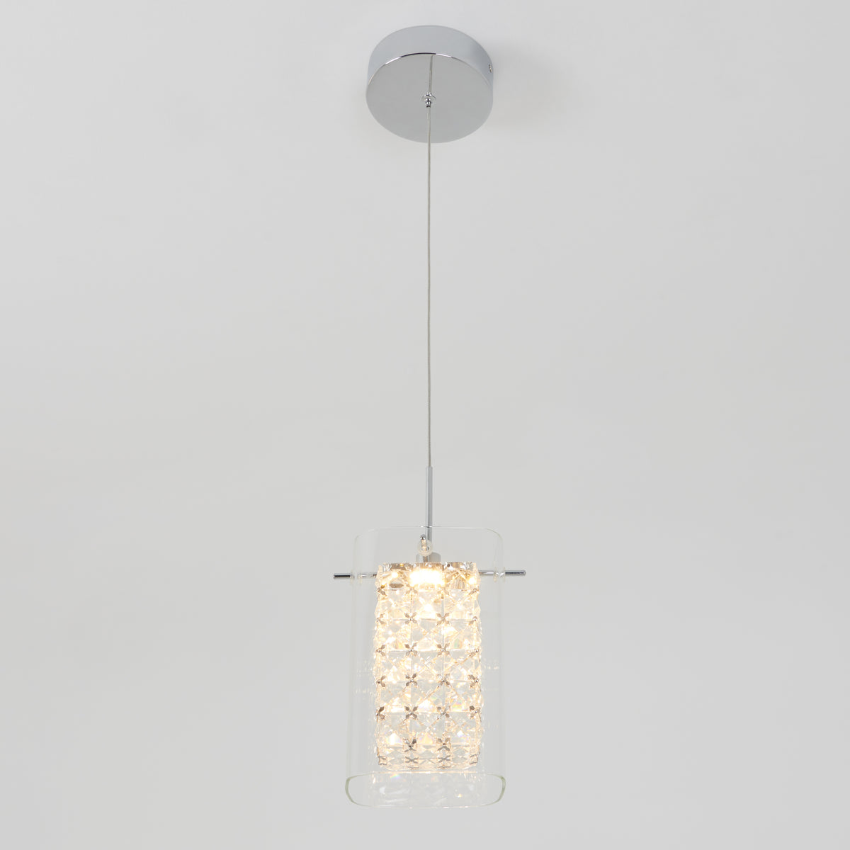 The Artika Crystal Cube 1-light LED pendant features a cylindrical glass shade with crystal-like accents, suspended by a thin wire from a chrome ceiling mount, shown against a plain white background.