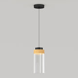 A modern pendant light with a black ceiling mount, black cord, and a cylindrical glass shade featuring a wooden accent near the top, hanging against a plain light gray background.