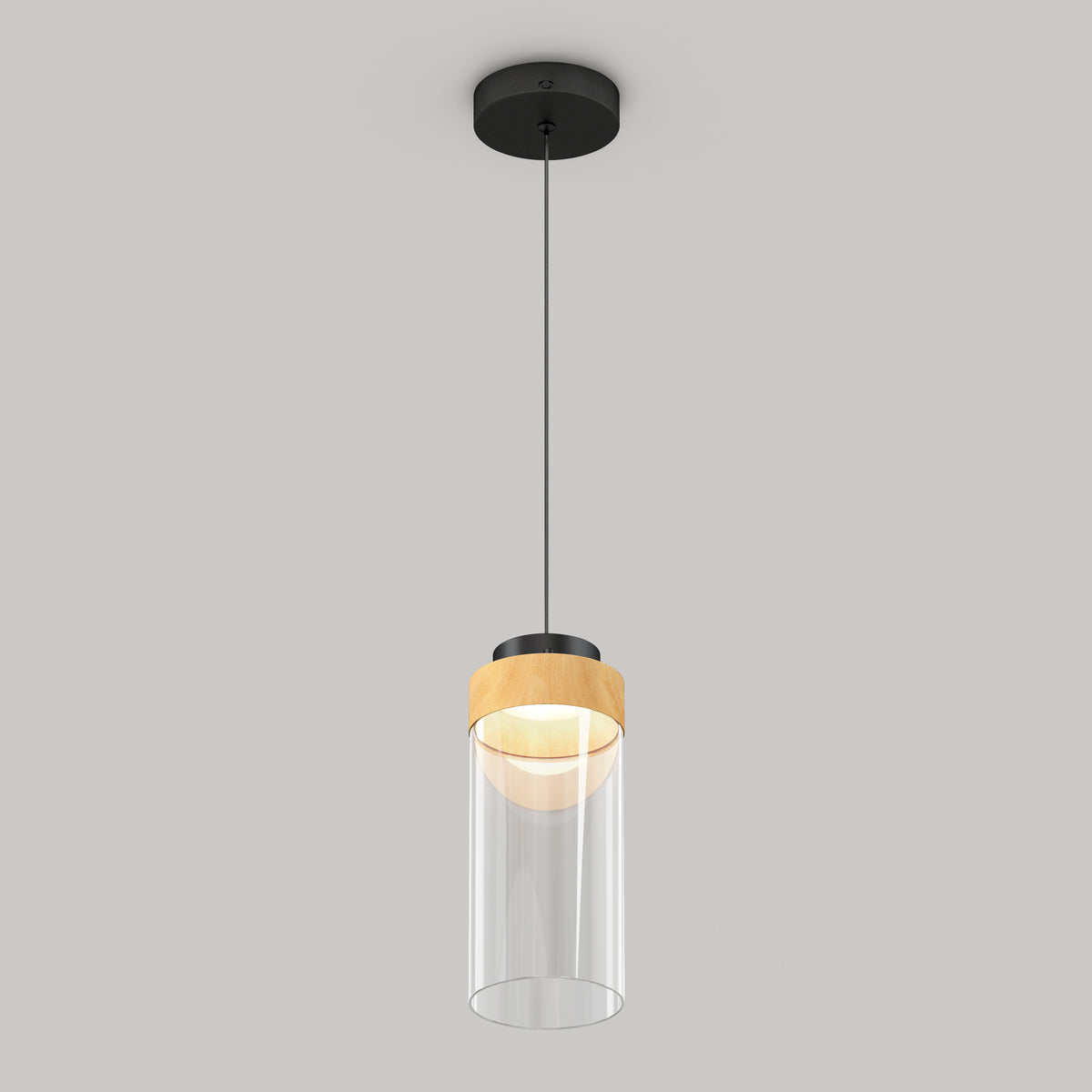A modern pendant ceiling light with a black mount, a thin black cord, a wooden accent, and a clear cylindrical glass shade, hanging against a plain light gray background.