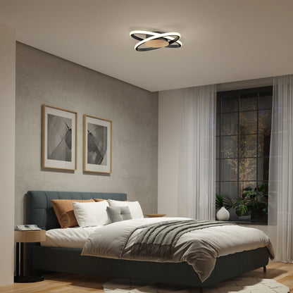 A modern bedroom with a double bed, gray and beige bedding, abstract wall art, large window with sheer curtains, potted plants, and an Artika Atomic 15 in. LED flush mount light with 5 CCT settings.