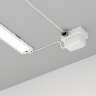 The Artika Maestro under cabinet LED light 3CCT, a white rectangular fixture, is connected by a white cable to a square white device mounted on the gray ceiling, with cables running neatly along the surface.