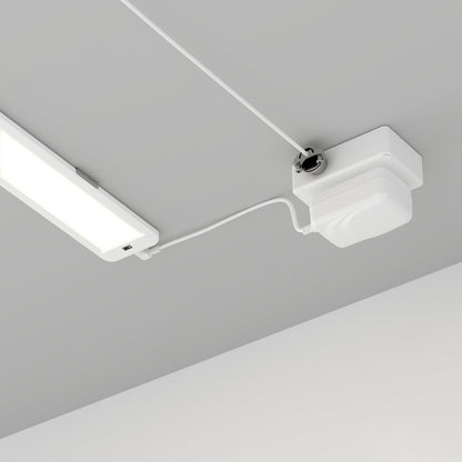 The Artika Maestro under cabinet LED light 3CCT, a white rectangular fixture, is connected by a white cable to a square white device mounted on the gray ceiling, with cables running neatly along the surface.
