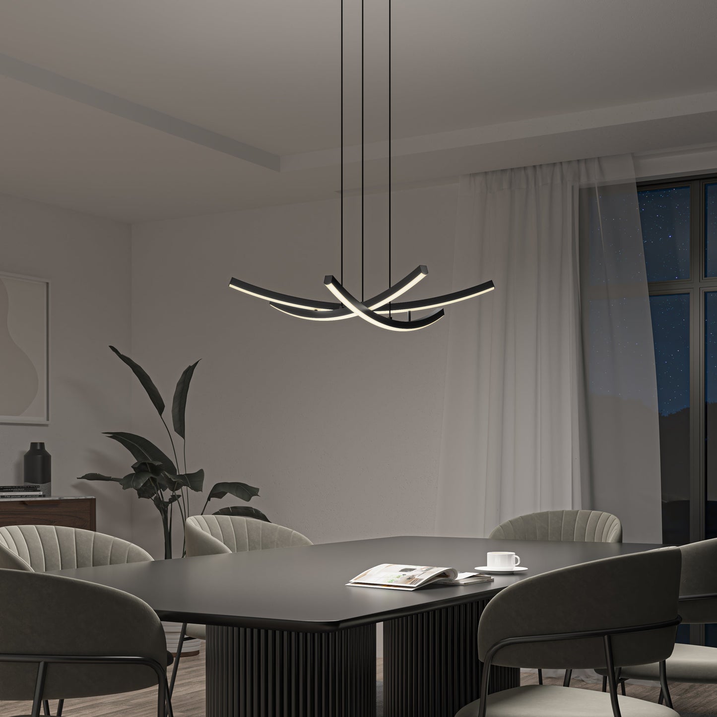 A modern dining room features a black table, gray upholstered chairs, the Orly modern LED pendant light by Artika-CAN-dev, a potted plant, a cup, and an open magazine. A large window offers a view of the night sky.