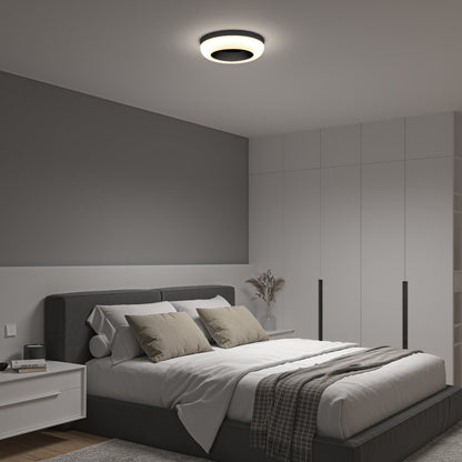A modern bedroom features a gray accent wall, white closet doors, a tidy bed with gray and beige pillows, a bedside table with a vase, and is illuminated by the Artika-CAN-dev Louka 15 in. modern LED flush mount light 5 CCT with adjustable brightness.