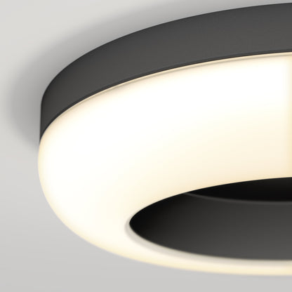 A close-up of the Artika-CAN-dev Louka 15 in. modern LED flush mount light 5 CCT, featuring a sleek black and white design with adjustable white hues for customizable ambiance, mounted on a light gray ceiling.
