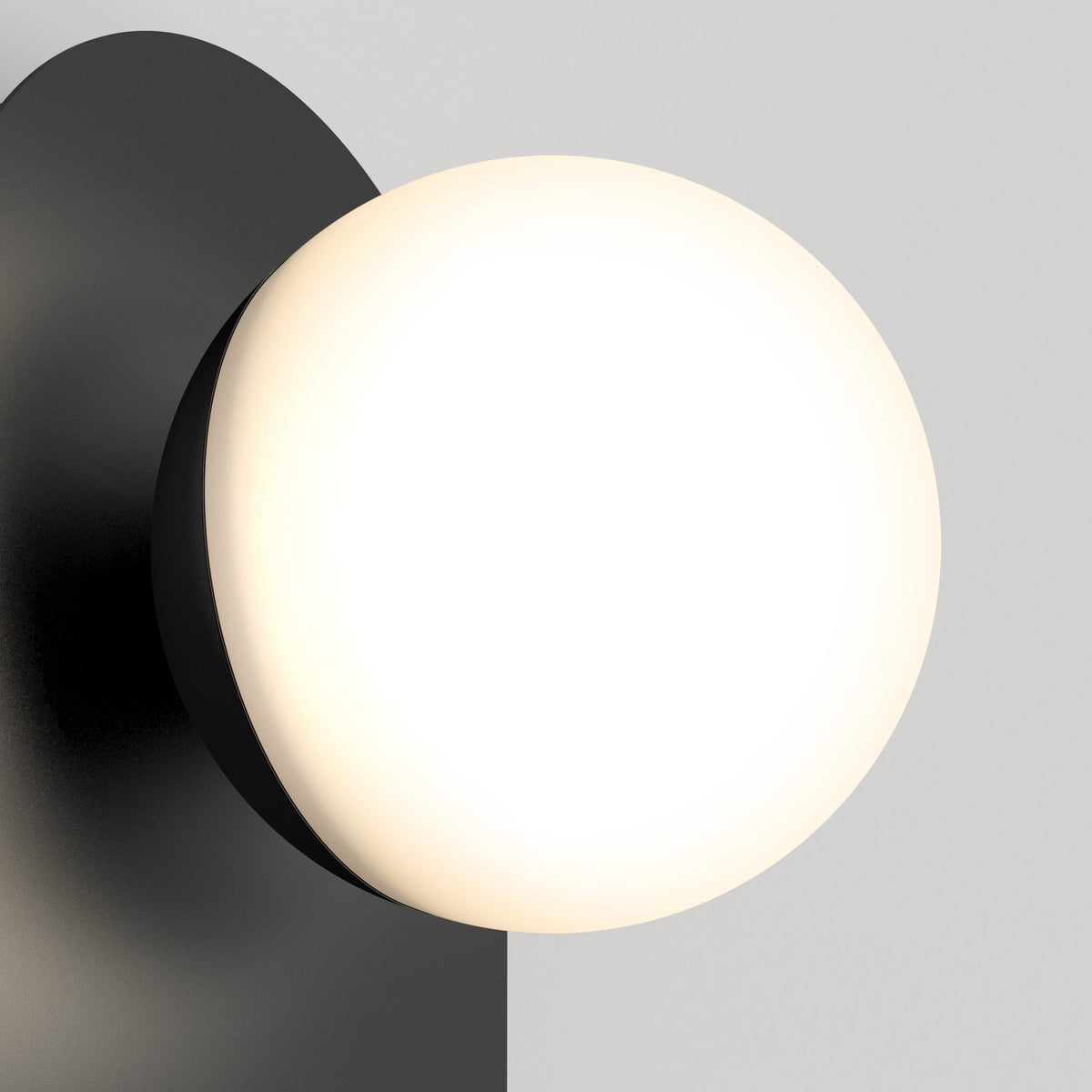 The Artika Bloomfield LED modern mid-century wall sconce 5 CCT features a matte black base and a large, round, frosted white glass bulb that provides soft, warm light against a light gray background.
