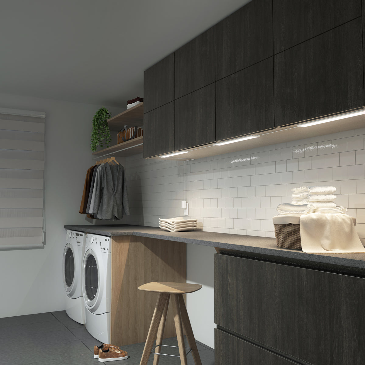 Modern laundry room with dark wood cabinets, a front-loading washer and dryer, folded towels on the counter, a wicker basket, hanging clothes, a potted plant, a stool, and white subway tile backsplash.