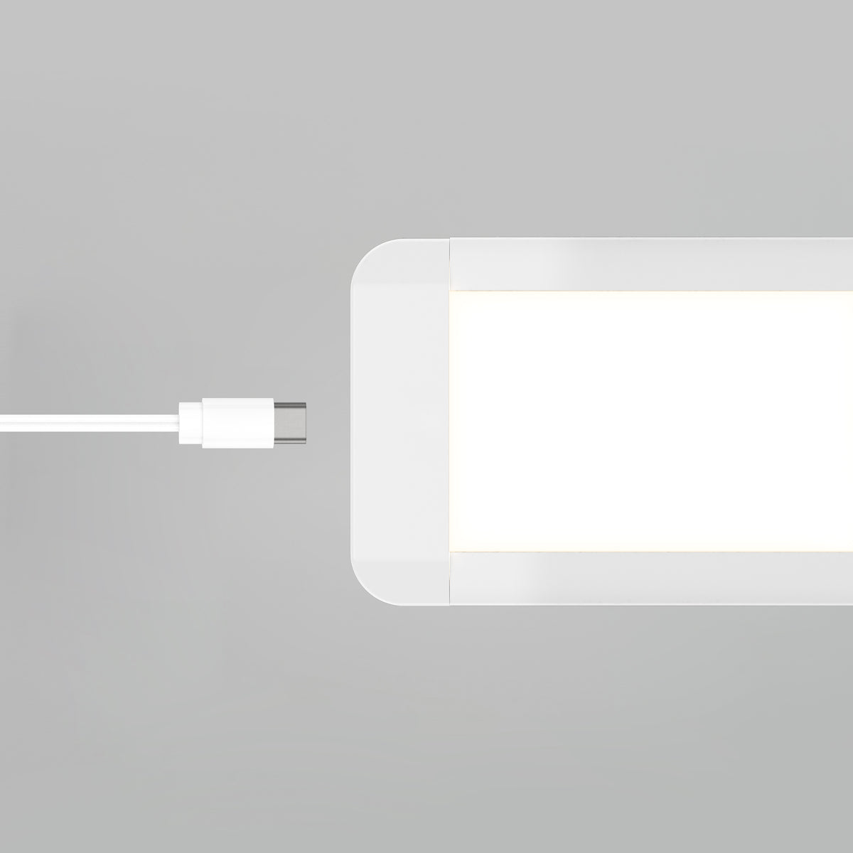 A white USB-C cable is positioned next to the corner of a rectangular, white-lit LED panel against a light gray background.