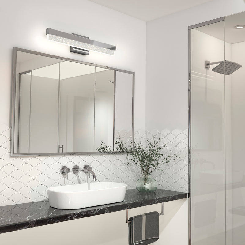 Modern bathroom with Artika's Essence Bubble Bar LED vanity light, vessel sink, large mirror, glass shower, and a vase with a plant.